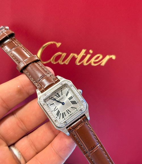 Montre Cartier Santos-Dumont avec lunette sertie de diamants et bracelet en cuir marron.