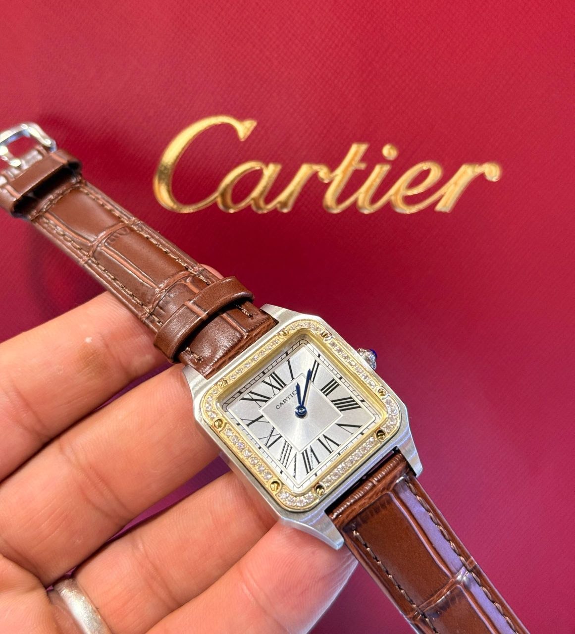 Montre Cartier Santos-Dumont avec lunette sertie de diamants et bracelet en cuir marron.